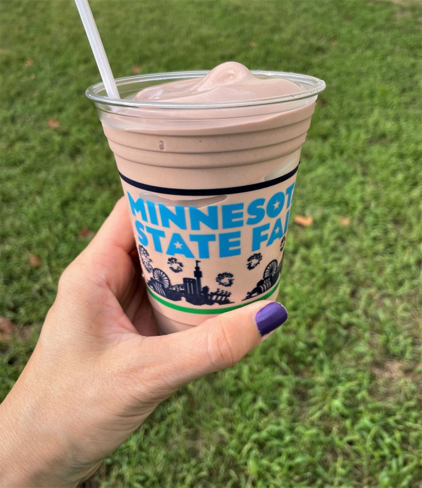 Hand holding a plastic cup filled with chocolate soft serve