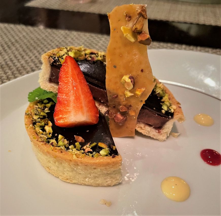 Chocolate tart garnished with a strawberry and pistachio brittle