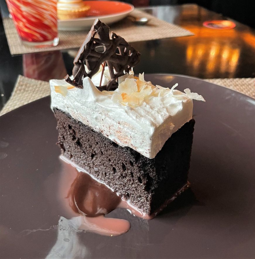 Piece of chocolate cake with coconut frosting and chocolate garnish