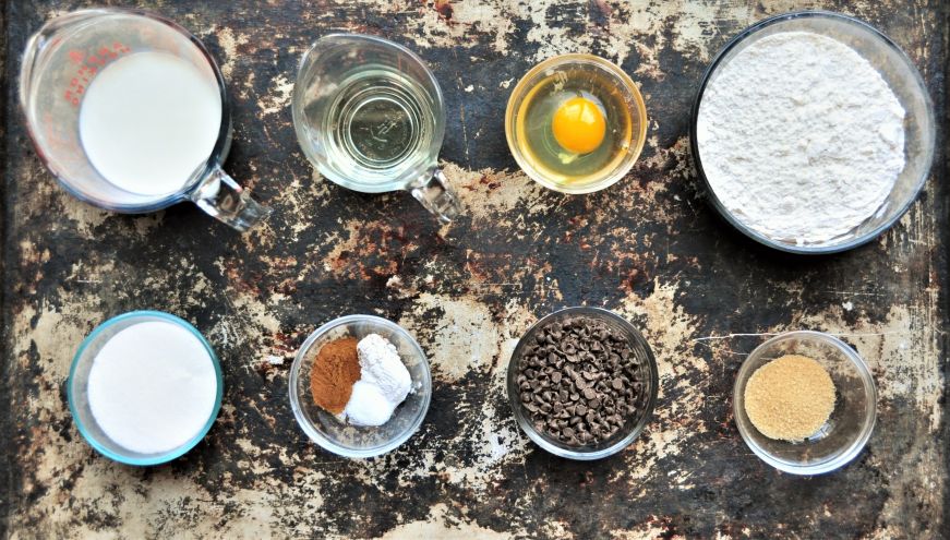 Top down view of of baking sheet with ingredients for cinnamon chocolate chip muffins