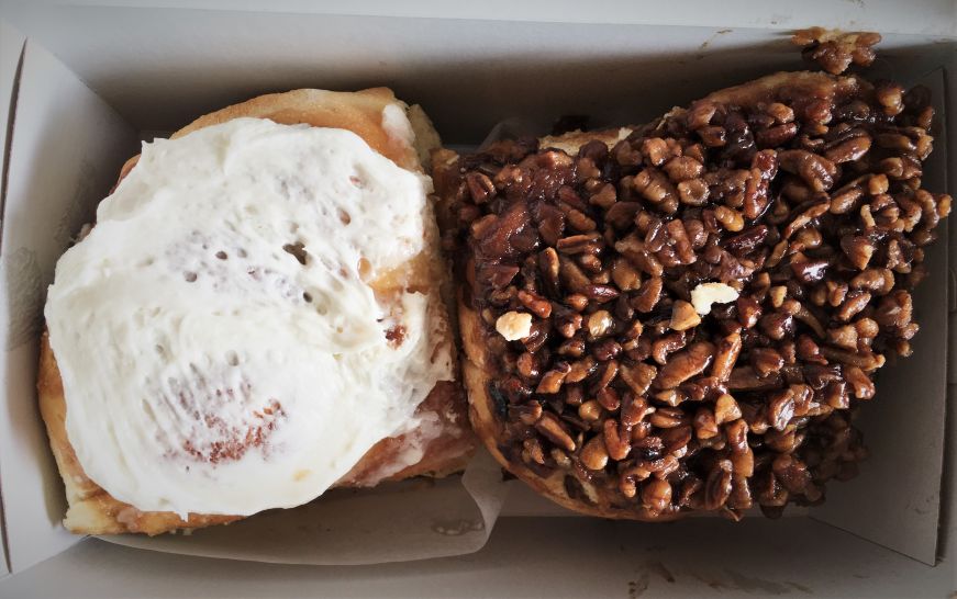 Cinnamon bun and caramel pecan bun in a takeout box