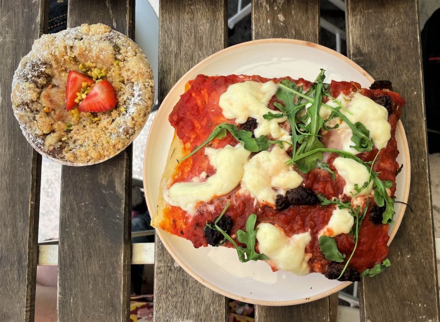 Top down view of an individually-sized clafoutis and piece of focaccia topped with tomato sauce, mozzarella, olives, and arugula