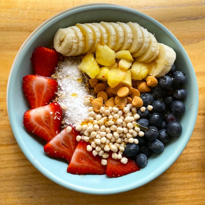 Smoothie bowl topped with fresh fruit, coconut, and butterscotch chips