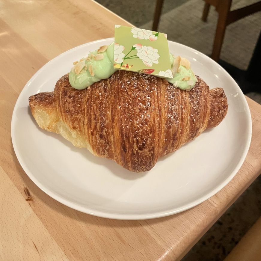 Coconut pandan croissant, Diane's Place Croissant garnished with a piece of chocolate decorated with a floral pattern