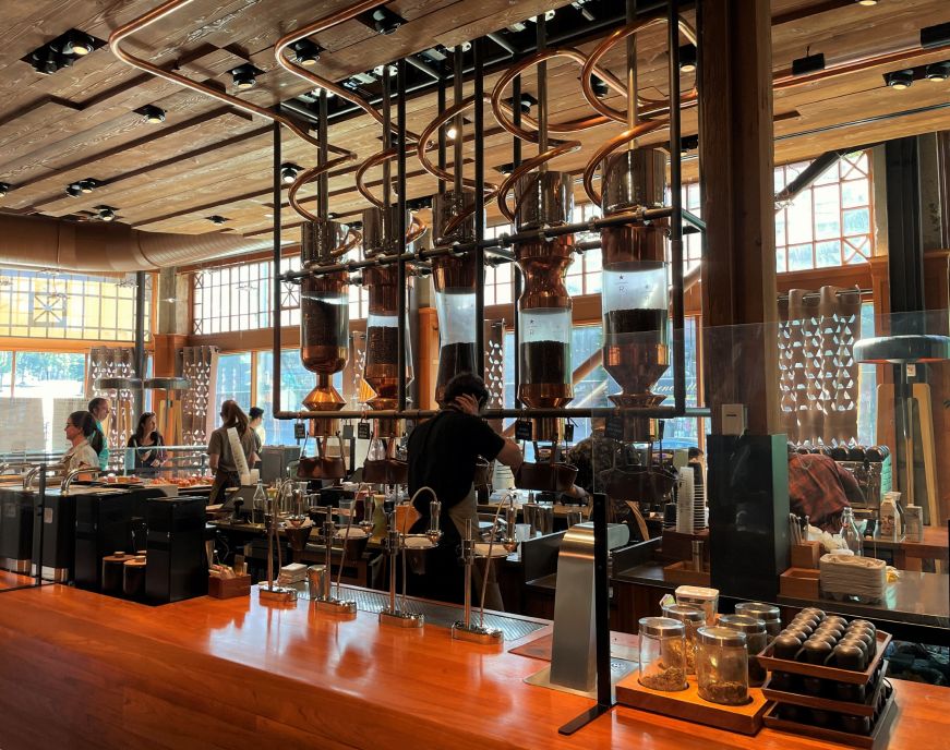 Wooden counter with coffee equipment and baristas working behind it