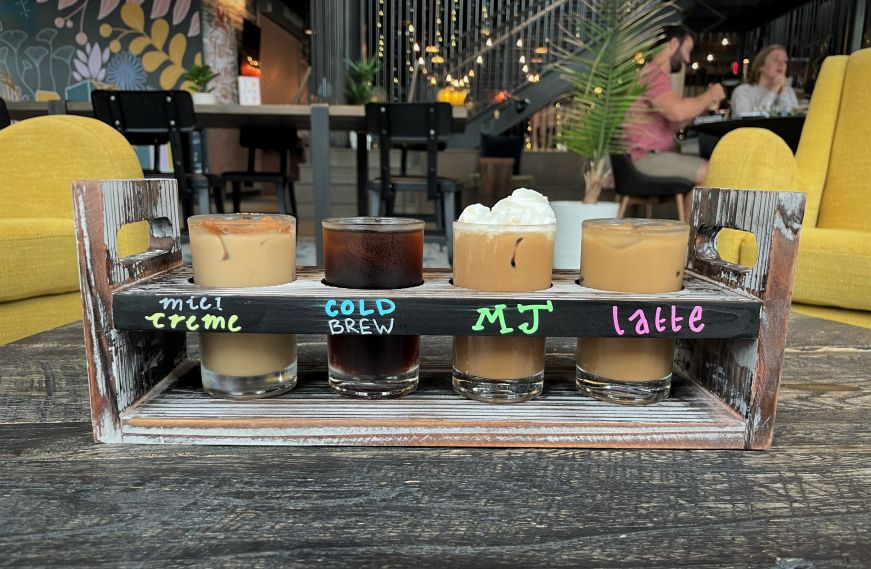 Four small glasses of cold brew in a wooden holder