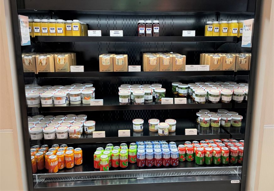 Cooler of grab-and-go items including canned beverages, sandwiches, and salads