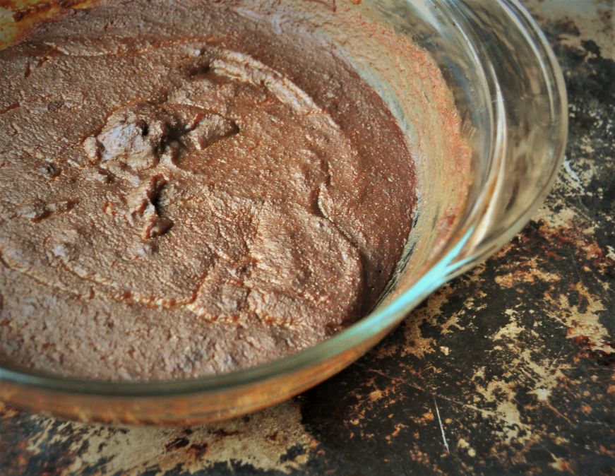 Close up view of cornmeal molasses pudding in glass baking dish