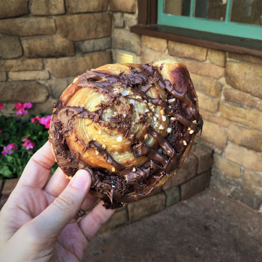 Hand holding round croissant drizzled with Nutella