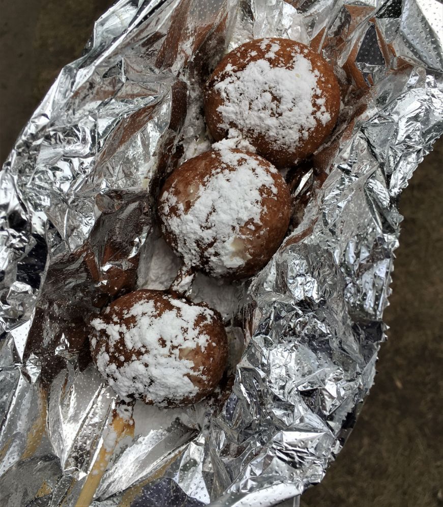 Three balls of battered deep fried cookie dough on a bamboo skewer