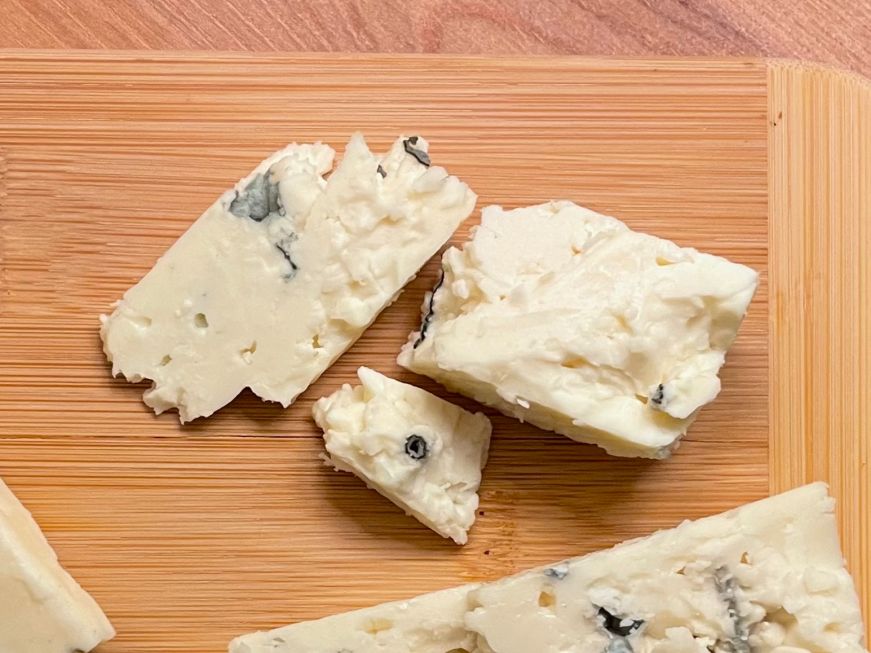 The Indigo Bunting, Deer Creek Cheese Pieces of blue cheese on a wooden board