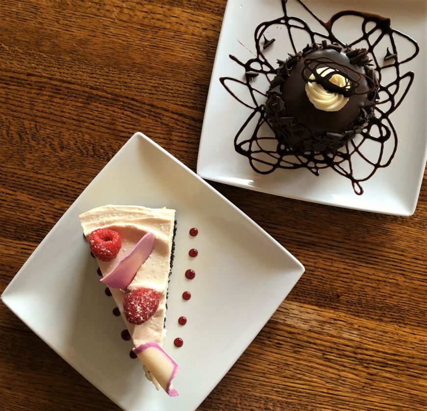 Top down view of slice of cheesecake and an individually-sized chocolate cake