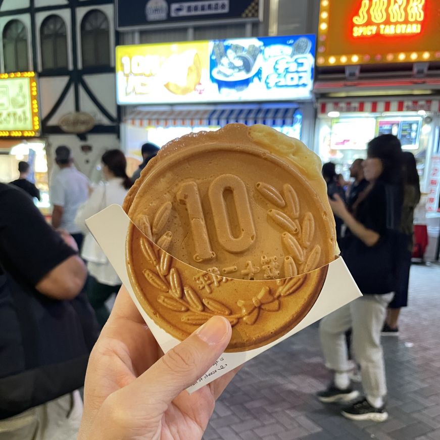 10 yen bread in Dotonbori, Osaka Stacy's hand holding a piece of crispy bread shaped like a 10 yen coin