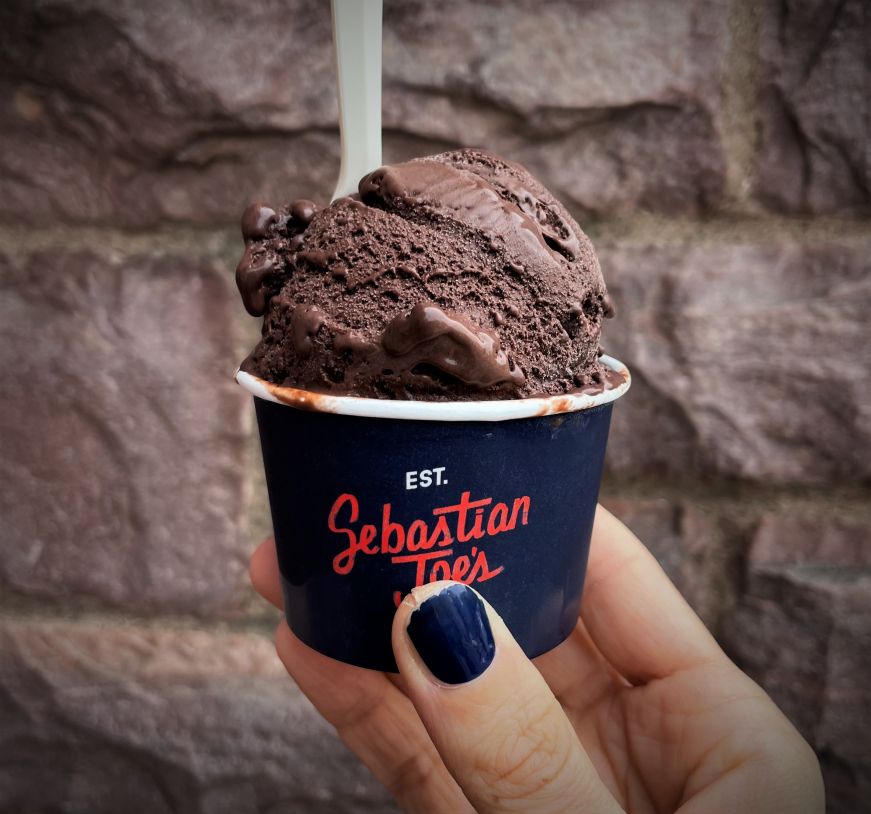 Hand holding a cup of chocolate ice cream with a Sebastian Joe's label