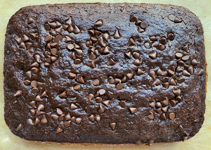 Chocolate cake topped with chocolate chips in a glass dish