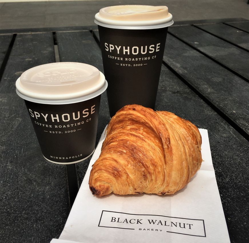 Two paper coffee cups with a croissant