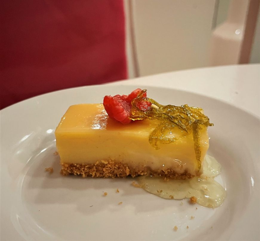 Small rectangular piece of lime pie garnished with a fresh raspberry