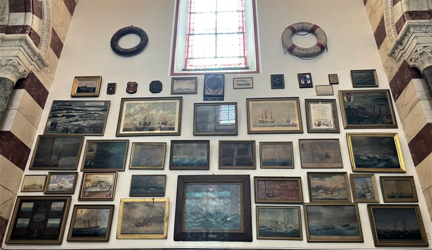 Church wall decorated with dozens of oil paintings depicting ships