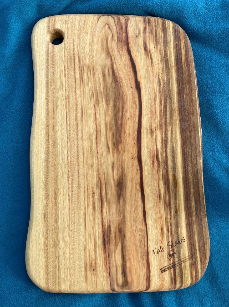 Wood cutting board on a blue picnic blanket