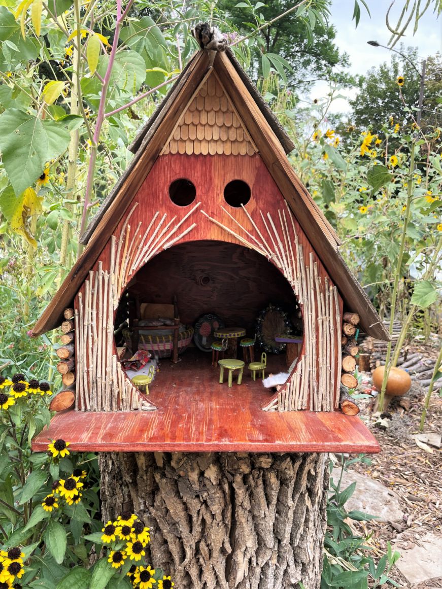 Bird house furnished with tiny furniture and surrounded with sunflowers