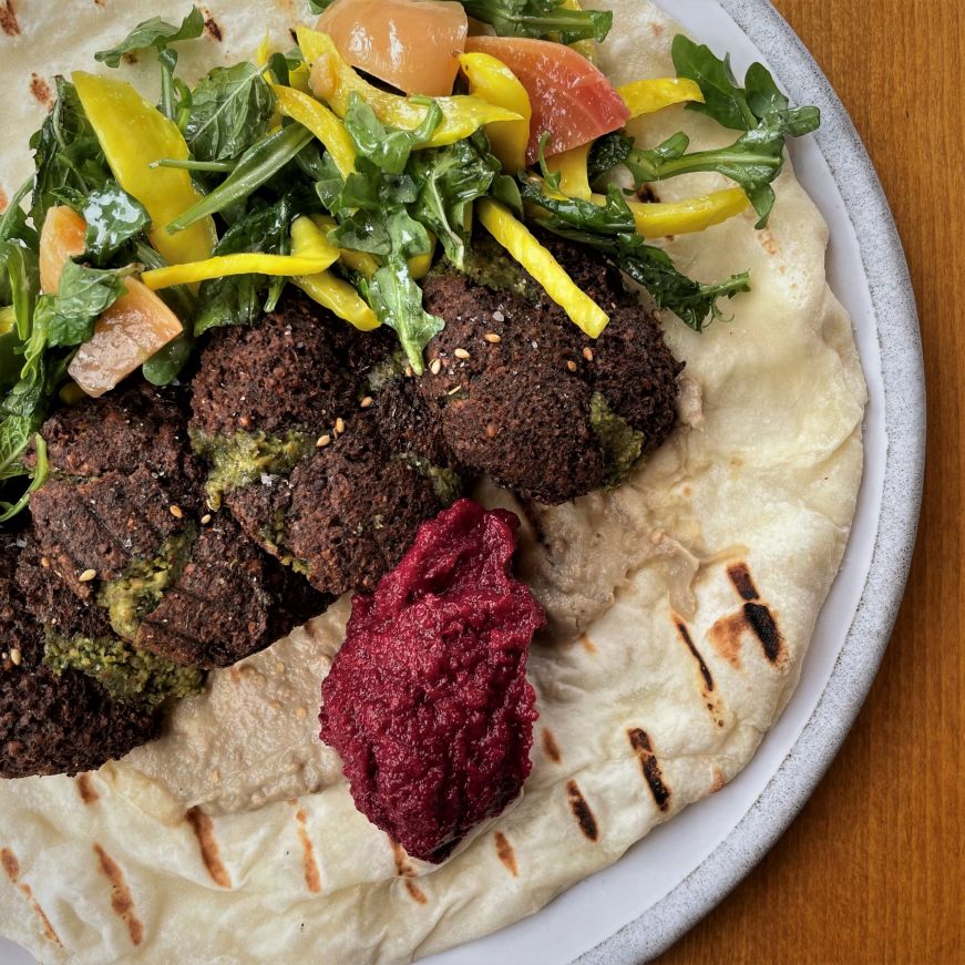Flatbread topped with falafel, greens, and a beet puree