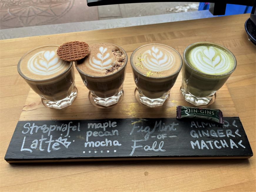 Flight of four small glass coffee glasses with latte art