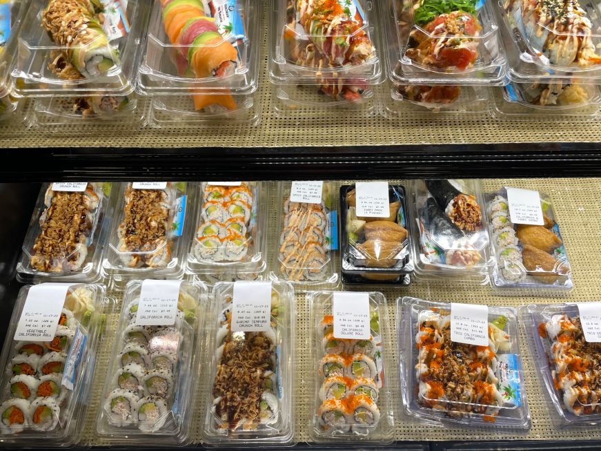 Containers of pre-made sushi in a grocery store cooler