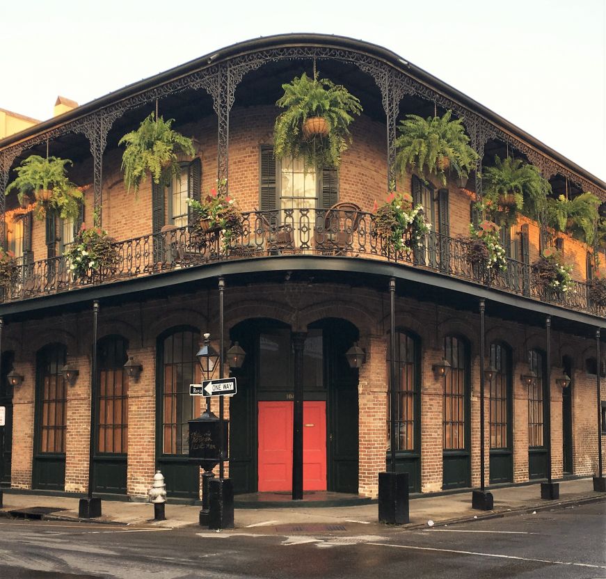Historic building in French Quarter with wrought iron balcony and hanging plants, New Orleans