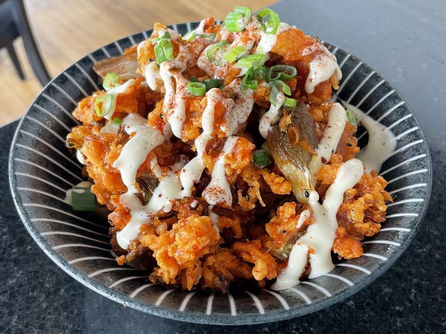 Bowl of deep-fried kimchi drizzled with a mayo