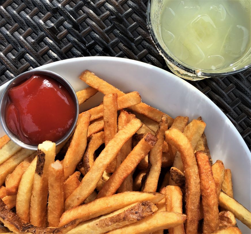 French fries with a cup of ketchup and cocktail with a salt rim