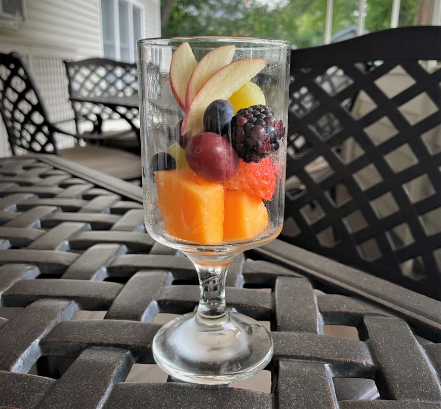 Goblet with an artistic arrangement of berries, grapes, and fanned apple slices