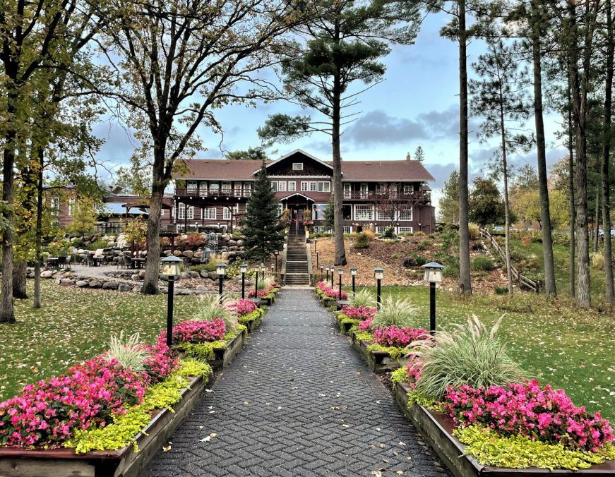 Flower lined path leading a large log-construction lodge building 