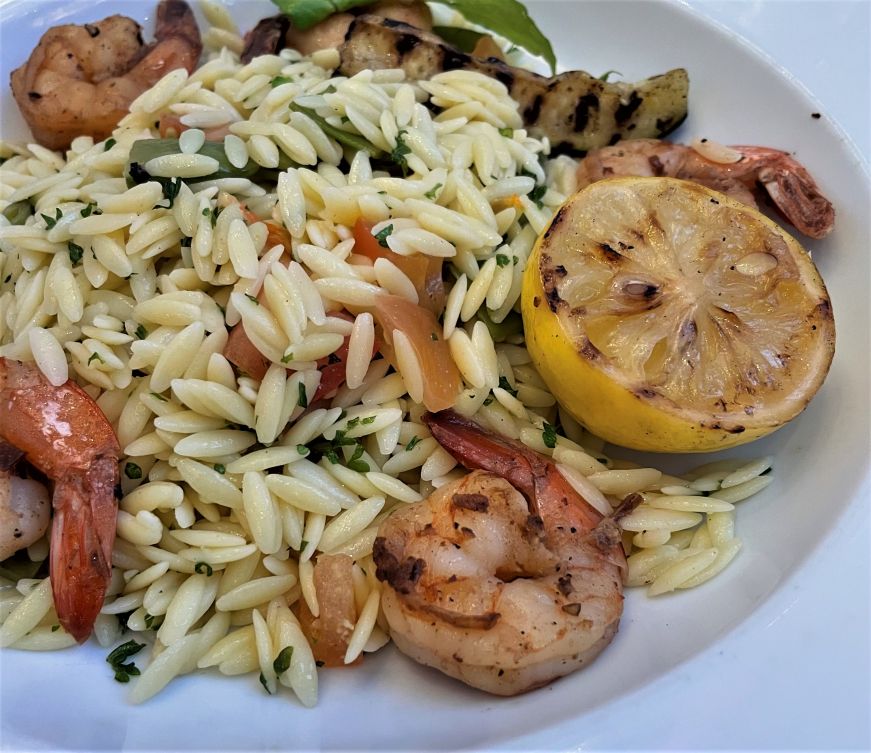 Plate of orzo with grilled shrimp and vegetables
