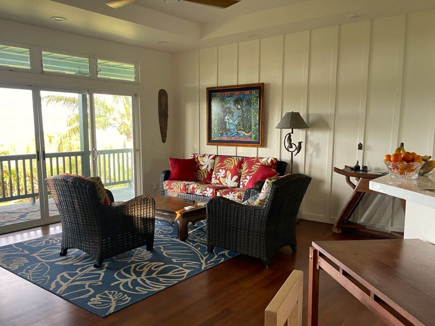 Living room at our bed and breakfast in Haʻikū-Pauwela Large living room opening onto a porch with a view of the ocean and palm trees