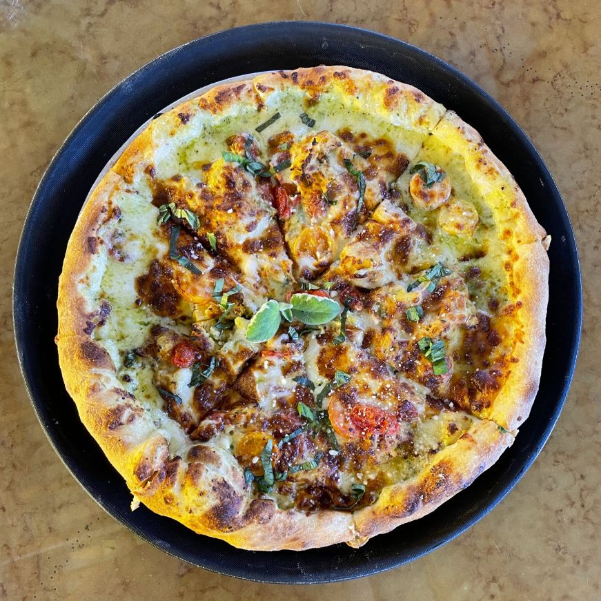 Top down view of a pizza topped with vegetables and breadfruit