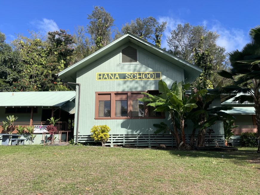 Green wood building with a sign reading "Hana School"