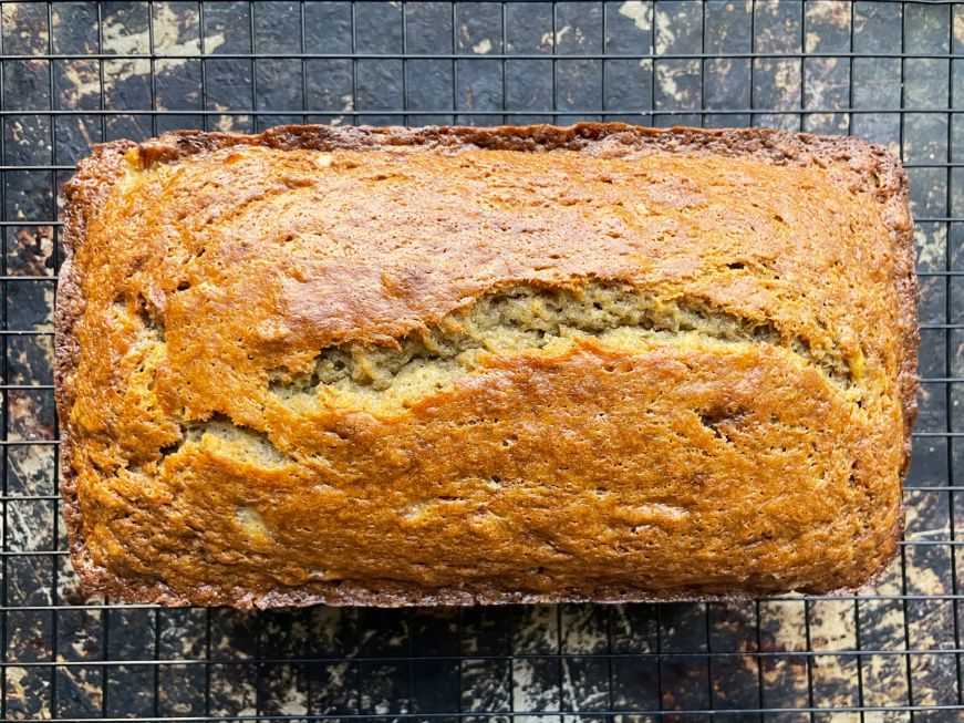 Top down view of a loaf of banana bread on a wire cooling rack