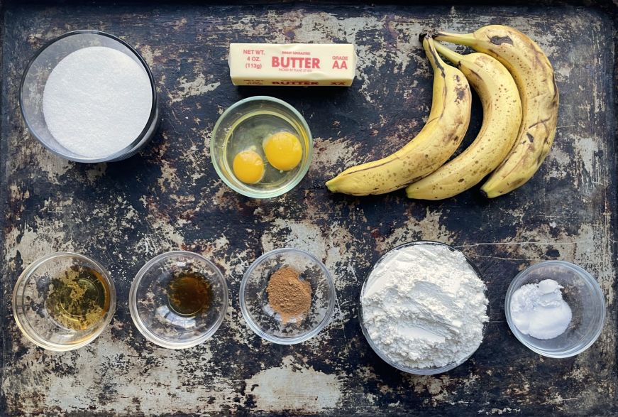 Top down view of banana bread ingredients arranged on a large baking sheet
