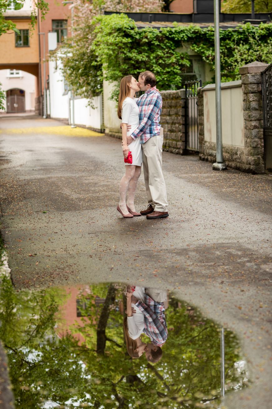 Stacy and Mike kissing in a side street in Helsinki, with their reflection in a puddle