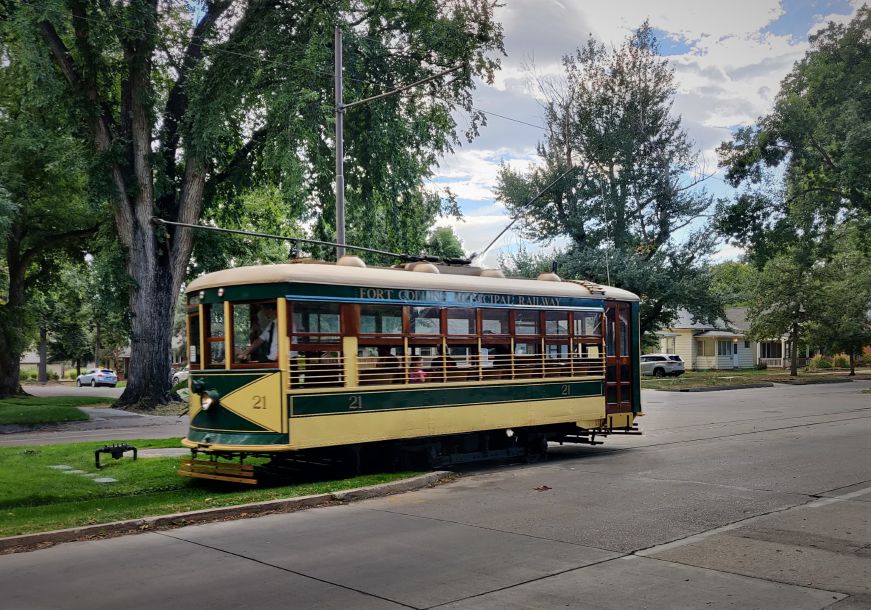 Historic trolley car going the grassy stretch in the middle of a street