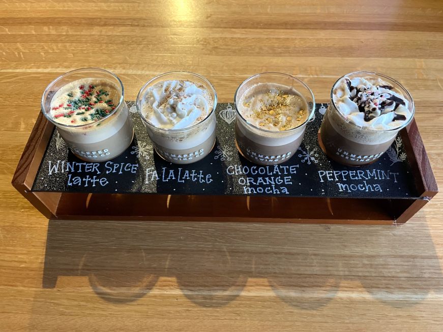 Flight of four holiday coffee drinks garnished with sprinkles