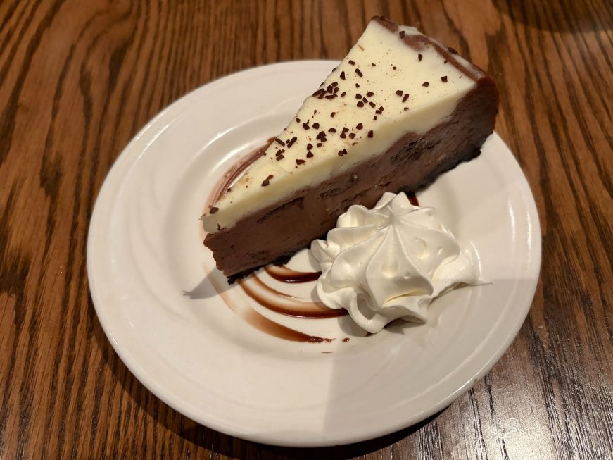 Slice of chocolate cheesecake topped with a cream layer and chocolate shavings