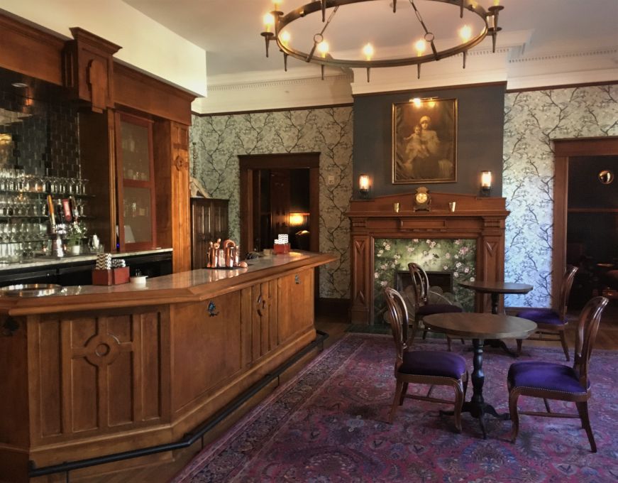 Hotel bar with old-fashioned woodwork, wallpaper, and fireplace