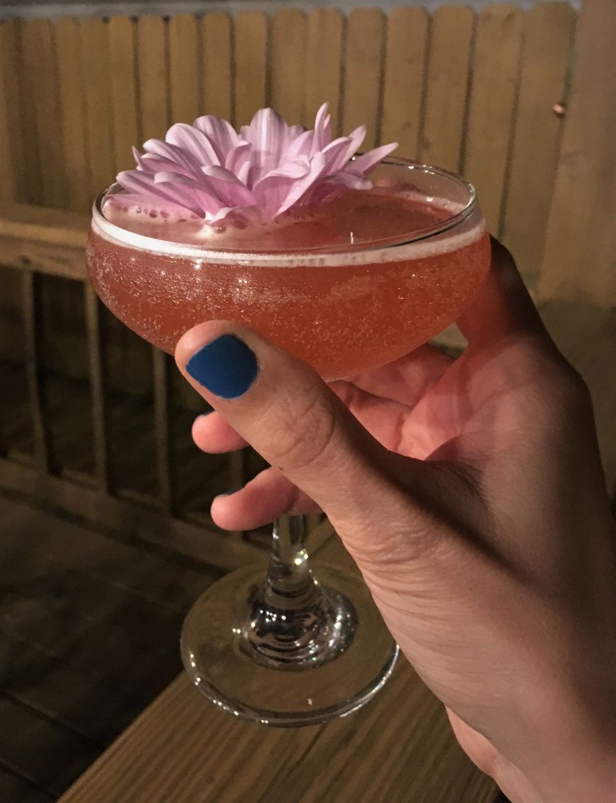Hand holding pink cocktail topped with a flower, The Mockingbird Lounge, Kansas City, Kansas