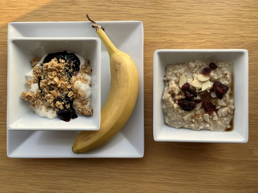 Breakfast at Hyatt Place Boston Seaport District Bowl of yogurt topped with blueberry compote and granola, banana, and bowl of oatmeal topped with dried cranberries and almonds