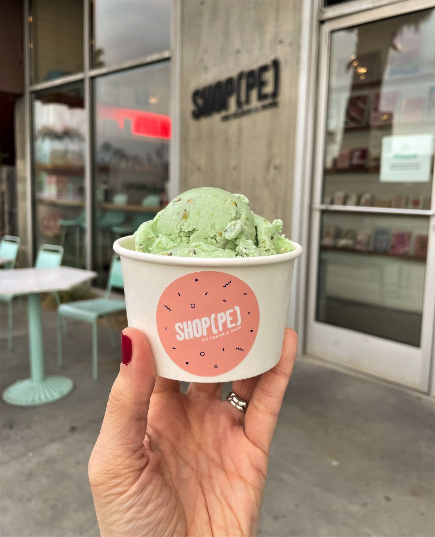 Stacy's hand holding a cup of bright green pistachio ice cream