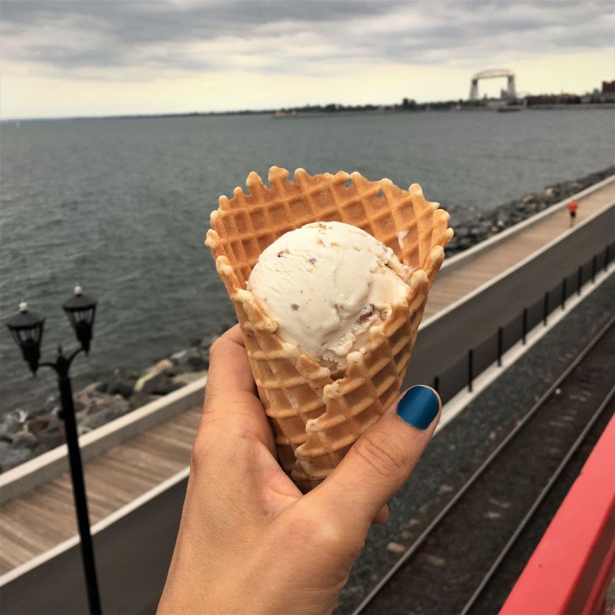Hand holding ice cream cone with Duluth's Aerial Lift Bridge and Lake Superior in the background