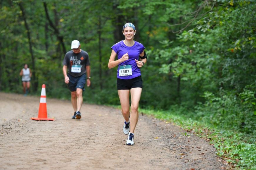 Stacy running with a race bib