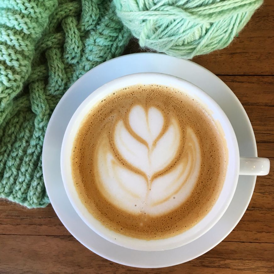 Latte with foam latte art and knitting project
