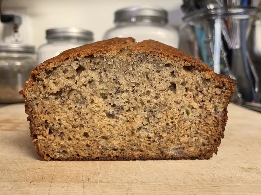 Cross section of a loaf of banana bread on a wooden cutting board